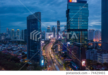 Aerial view of multi lane highway through modern city center with tall skyscrapers in blue evening light Night time traffic through downtown Jakarta, Indonesia Aerial view of multi lane highway through modern city center with tall skyscrapers in blue evening light Night time traffic through downtown Jakarta, Indonesia 74429401