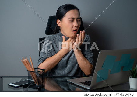Asian woman was sick with fever, working on a laptop. 74430476