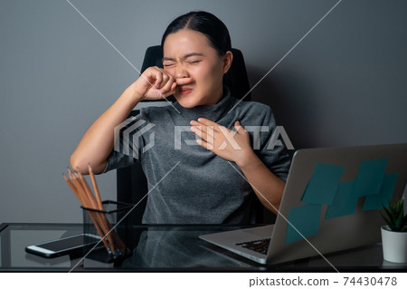 Asian woman was sick with fever, working on a laptop. 74430478