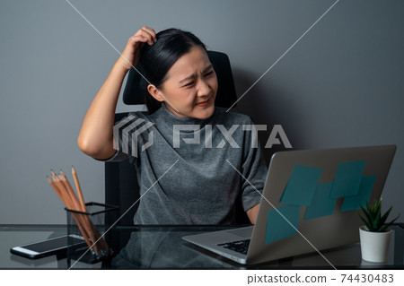 Asian woman scratching her head at office. Asian woman scratching her head at office. 74430483