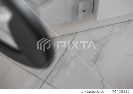 Spilled water leaked from washing machine built into the kitchen furniture. Spilled water on the tiled floor, flooding. 74430812