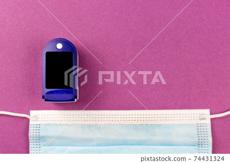 Medical mask and oximeter on a pink background. Copy space Medical mask and oximeter on a pink background. Copy space 74431324