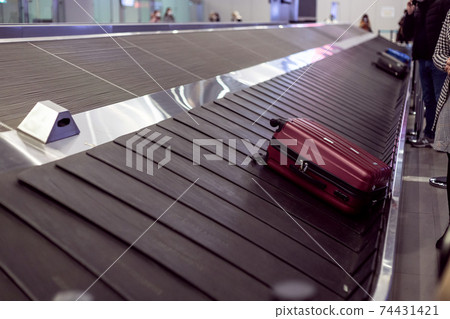 Suitcase on luggage conveyor in the baggage claim area at the airport. Lockdown Suitcase on luggage conveyor in the baggage claim area at the airport. Lockdown 74431421