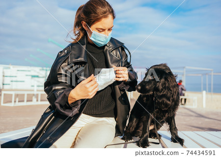 Young woman in medical mask puts on protective mask 74434591