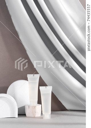 White cosmetic products tube on stand with fabric drapery. Mockup in right side 74435557
