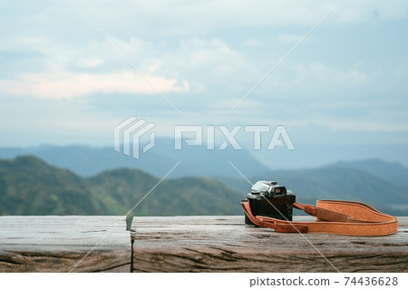 vintage camera put on wooden countertop with mountain background 74436628