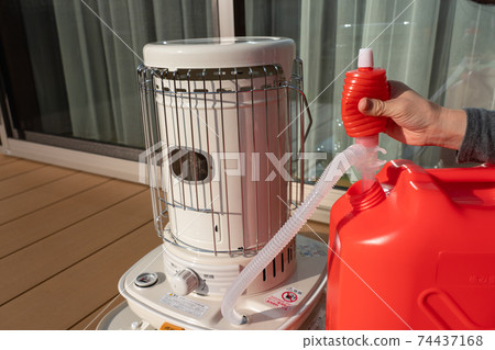 Refueling an oil stove, women's hands, winter Refueling an oil stove, women's hands, winter 74437168