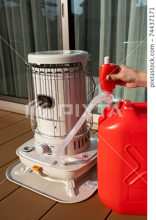 Refueling an oil stove, women's hands, winter 74437171