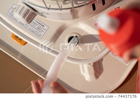 Refueling an oil stove, women's hands, winter Refueling an oil stove, women's hands, winter 74437176