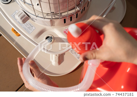 Refueling an oil stove, women's hands, winter 74437181
