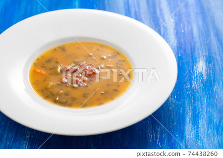 soup with smoked meat in white plate on wooden background 74438260