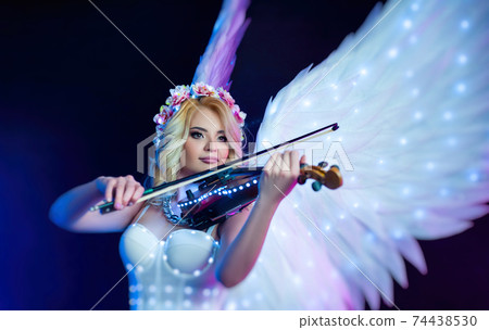 women with angel wings playing violin in neon light 74438530