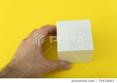 Mans hand holds small white cardboard box. Copy space. Mock up. Mans hand holds small white cardboard box. Copy space. Mock up. 74438663