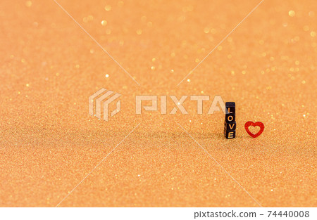 The inscription love is made of wooden letters and a red heart on a gold iridescent background. The inscription love is made of wooden letters and a red heart on a gold iridescent background. 74440008