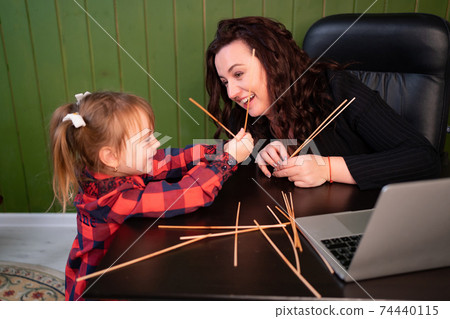 the little daughter prevents the freelancer mother from working on the computer. the little daughter prevents the freelancer mother from working on the computer. 74440115
