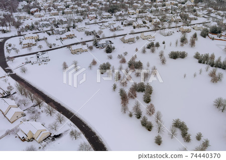 Aerial view of snowed in traditional housing estate the suburbs in dangerous weather conditions Aerial view of snowed in traditional housing estate the suburbs in dangerous weather conditions 74440370