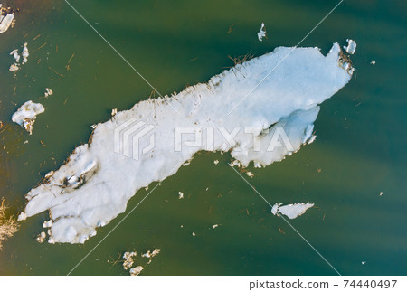 Pieces of melting ice under the bright spring sun on the river bank Pieces of melting ice under the bright spring sun on the river bank 74440497