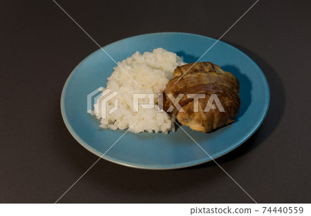 Boiled white rice with chicken cutlet wrapped in bacon on a gray background blue plate. 74440559