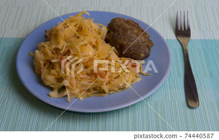 Stewed white cabbage with a cutlet steak on a plate. A dish of Russian, Polish cuisine. Garnish in the USSR. 74440587