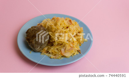 Stewed white cabbage with a cutlet steak on a plate. A dish of Russian, Polish cuisine. Garnish in the USSR. 74440591