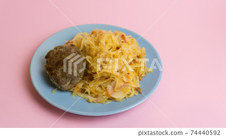 Stewed white cabbage with a cutlet steak on a plate. A dish of Russian, Polish cuisine. Garnish in the USSR. Stewed white cabbage with a cutlet steak on a plate. A dish of Russian, Polish cuisine. Garnish in the USSR. 74440592
