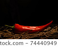 red hot chili peppers lie on dry grass and a metal grill 74440949