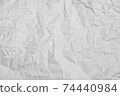 a crumpled white sheet of paper on a black background. 74440984