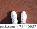 men's feet in white socks and sneakers on a sports treadmill. 74440987
