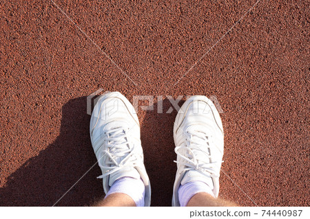 men's feet in white socks and sneakers on a sports treadmill. 74440987