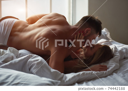 Young lovers kissing in bed. 74442188