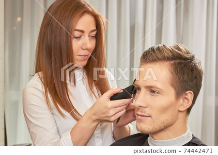Female barber using hair clipper. Female barber using hair clipper. 74442471
