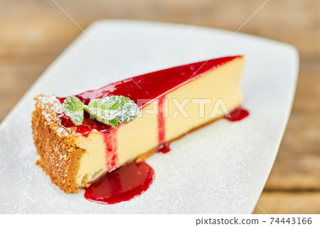 Close up delicious piece of cheesecake with red jam and mint leaves. Close up delicious piece of cheesecake with red jam and mint leaves. 74443166