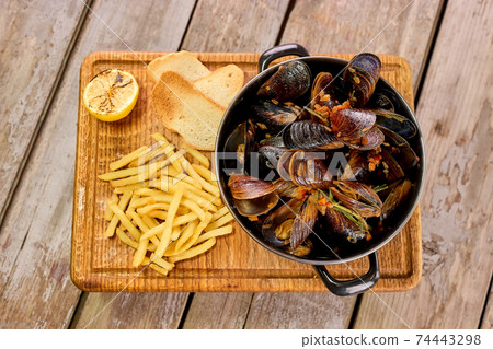 Shellfish mussels in saucepan with lemon and fries. Shellfish mussels in saucepan with lemon and fries. 74443298
