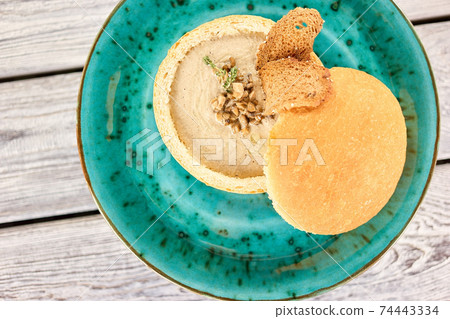 Mushroom cream soup with toast and thyme in bread bowl. 74443334