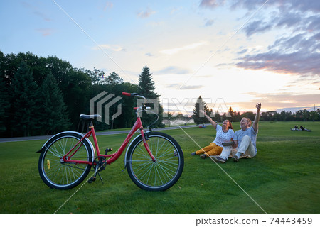 Happy mature couple sits on the lawn. 74443459