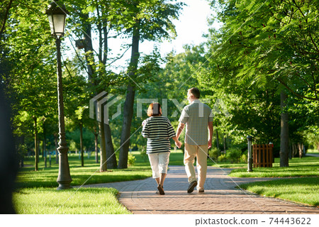 Couple holding hands in the park. Couple holding hands in the park. 74443622
