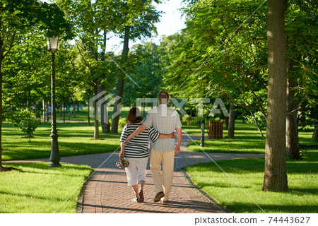 Walking couple in the green summer park. Walking couple in the green summer park. 74443627