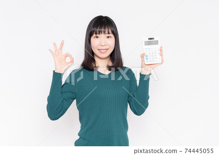 站立在白色背景前面和顯示計算器的一名微笑的婦女 74445055