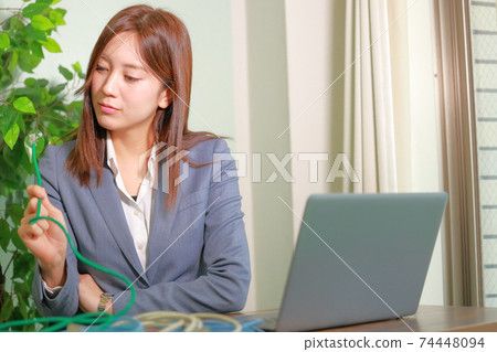A woman thinking with a LAN cable 74448094