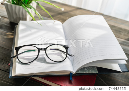 Reading glasses put on open book Reading glasses put on open book 74448335