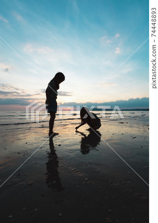 Silhouette of two asian child girls playing on the beach together at the sunset time with beautiful sea and sky. Family enjoy with nature concept. Silhouette of two asian child girls playing on the beach together at the sunset time with beautiful sea and sky. Family enjoy with nature concept. 74448893
