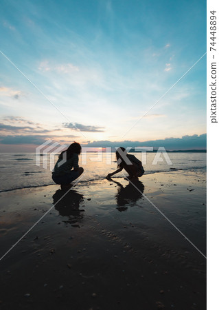 Silhouette of two asian child girls playing on the beach together at the sunset time with beautiful sea and sky. Family enjoy with nature concept. Silhouette of two asian child girls playing on the beach together at the sunset time with beautiful sea and sky. Family enjoy with nature concept. 74448894