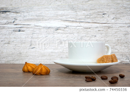 white coffee cup with small cookies on wooden table 74450336