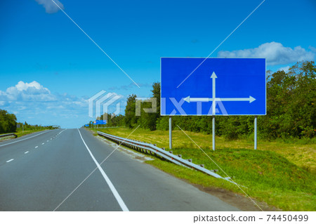 blank blue billboard with arrow directions near empty motorway 74450499