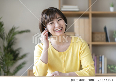 A young woman looking at the camera with wireless headphones 74453494