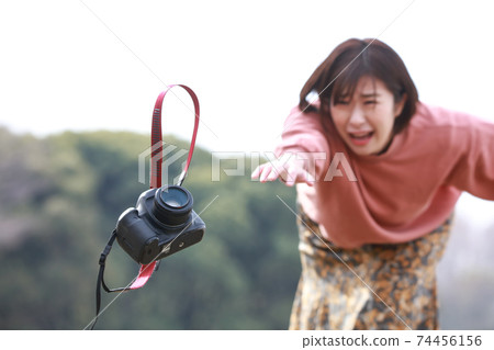 A woman who is about to drop a single-lens reflex camera 74456156