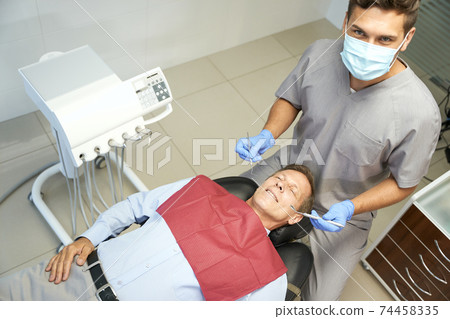 Ambitious young dental specialist posing with his patient 74458335