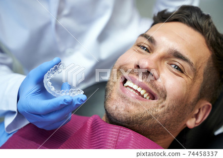 Silicone teeth mold for a young man in dental chair 74458337