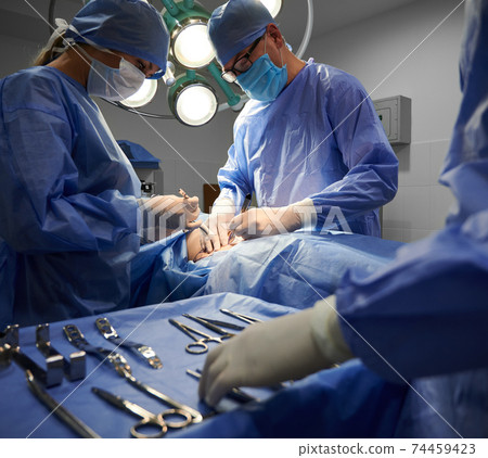 Surgical team doing plastic surgery and using medical insturments. 74459423