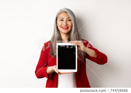 Business. Proud asian female manager showing blank digital tablet screen, smiling and demonstrating promo, standing over white background 74459986